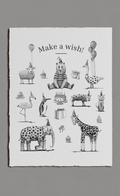 Tea towel with illustrations of animals and text 'Make a wish!' on a gray background